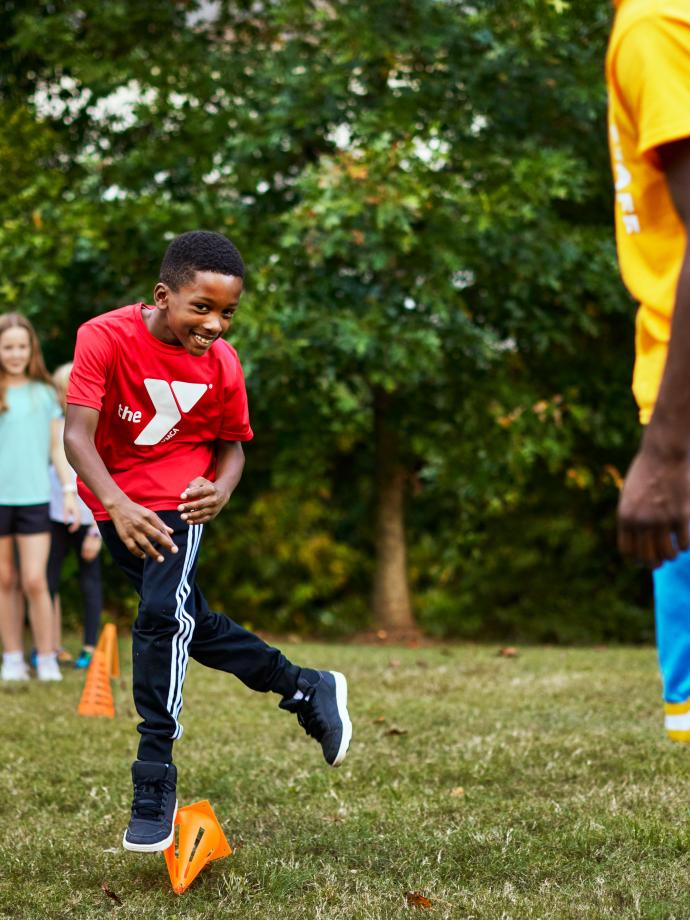 Throwing Ball In Field At YMCA Healthy Kids Day