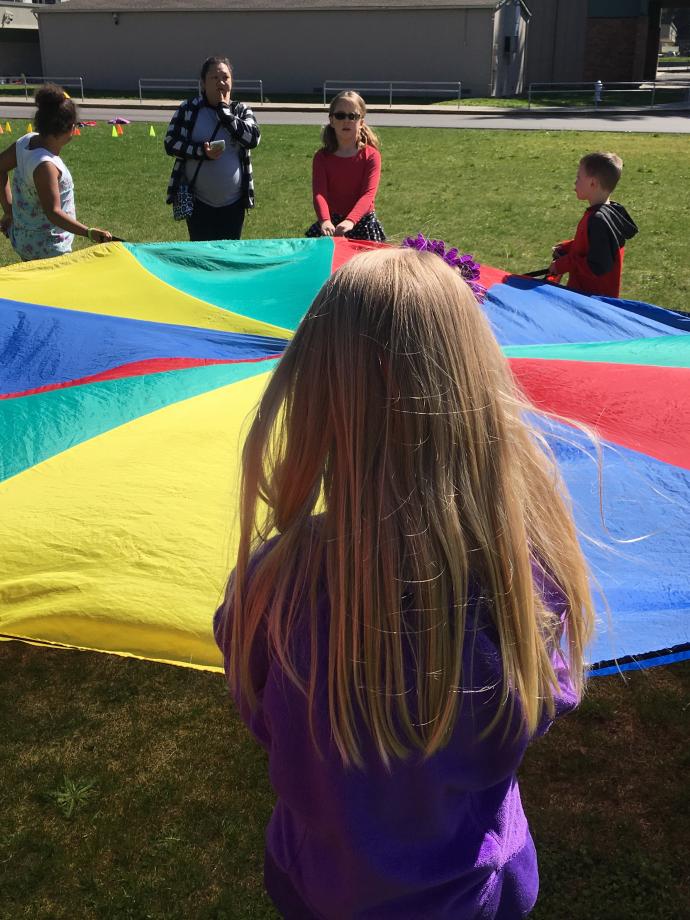 Kids playing with team parachute toy in field