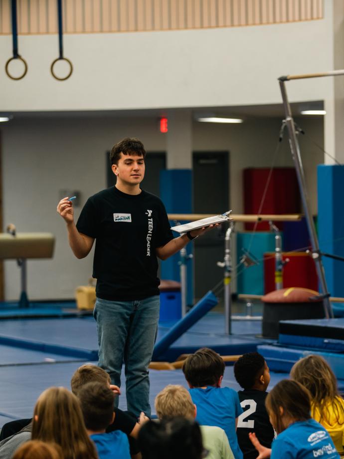 Teen leader stands to speak in front of kids night out participants
