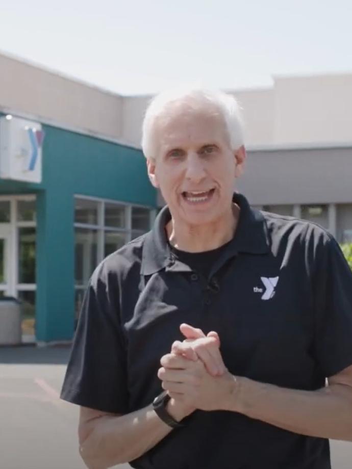 YMCA PKC CEO Charlie Davis giving a speech in front of a YMCA community center