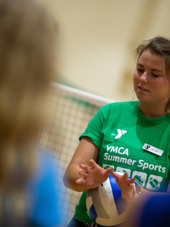 Volleyball coach demonstrates proper hand position for a set at the YMCA