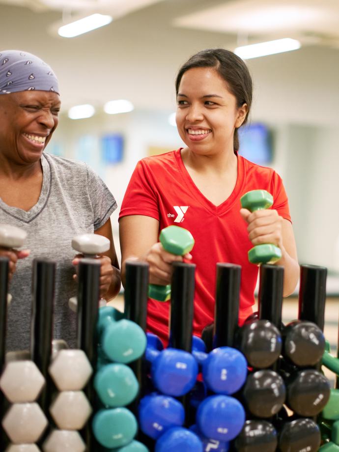 Group exercise participant selects dumbbells for a workout at the YMCA