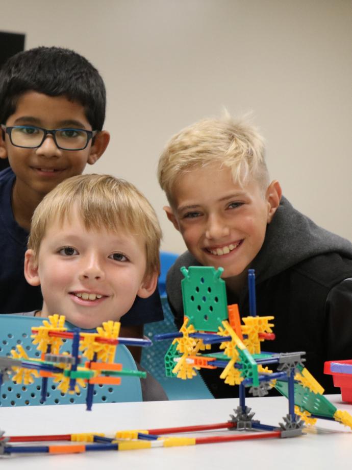 Summer camp participants pose behind a Kinex building block creation at the YMCA