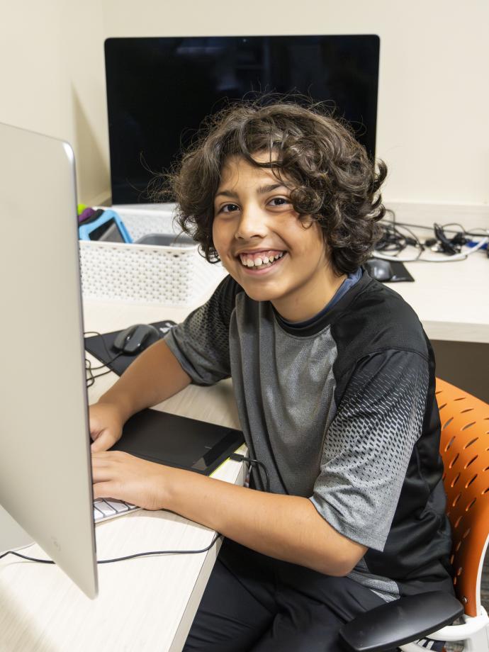 Digital arts student smiles at the computer at the YMCA
