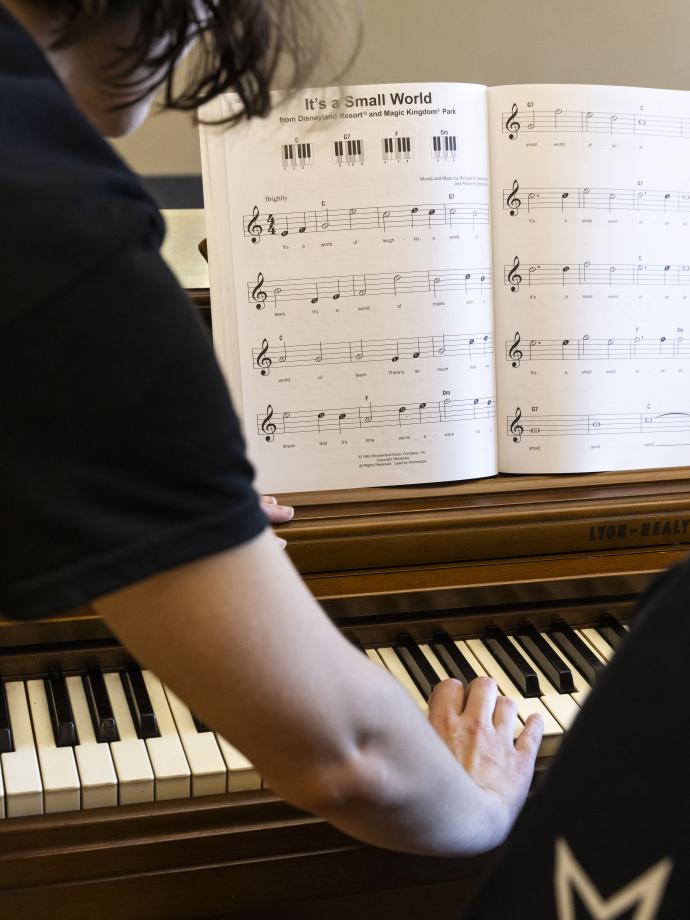 Music student observes a piano chord demonstrated by an instructor at the YMCA