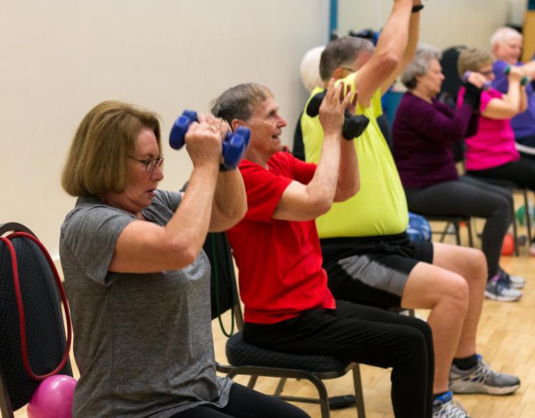 Active older adults lift weights in a senior strength class to improve balance, flexibility, strength, and stability.