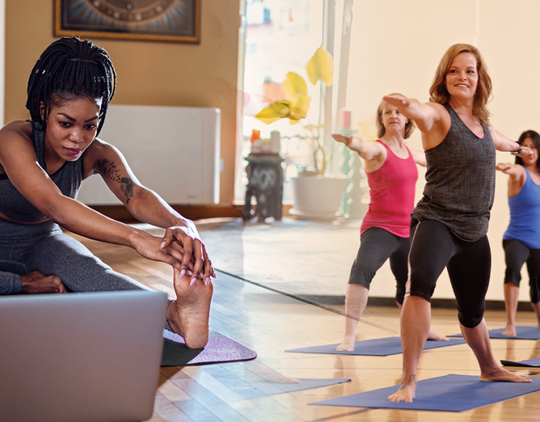 Image of person doing yoga at home stitched with image of gym yoga session