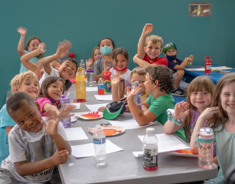 Youth wave while doing crafts at ELC