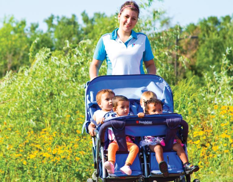 Y staff member taking toddlers on a stroller walk