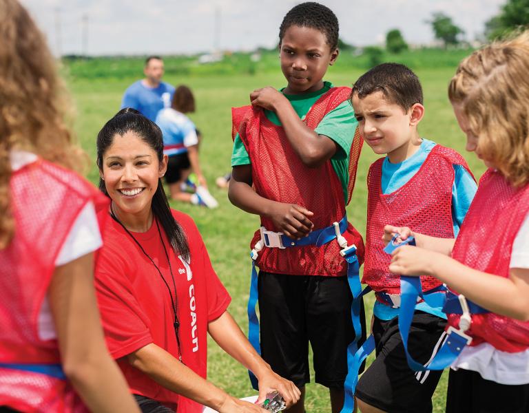 Flag football team huddles around coach