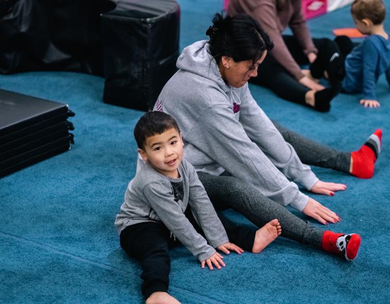 Toddler gym participant and parent stretch before a session