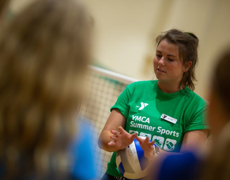 Volleyball coach demonstrates proper hand position for a set at the YMCA