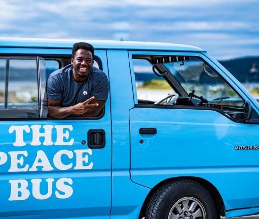 Kwabi throws up a peace sign from the window of his Peace Bus