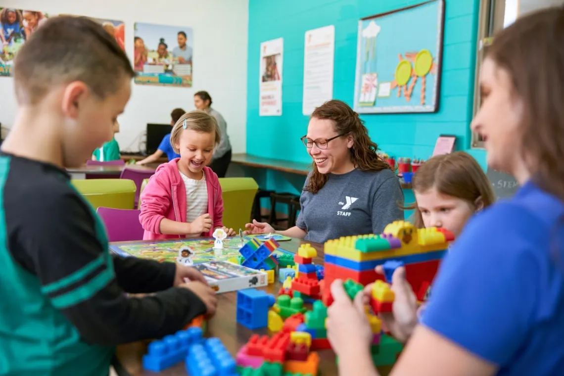 Childcare staff and youth playing board games and legos
