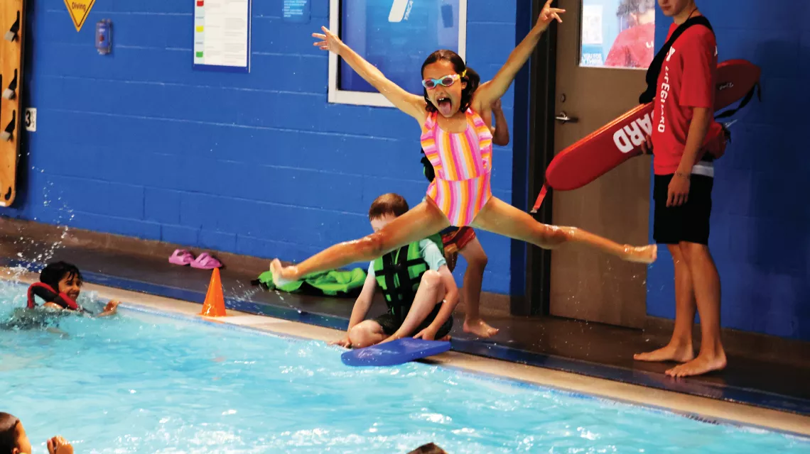 YMCA member strikes a pose while jumping into the swimming pool at the YMCA