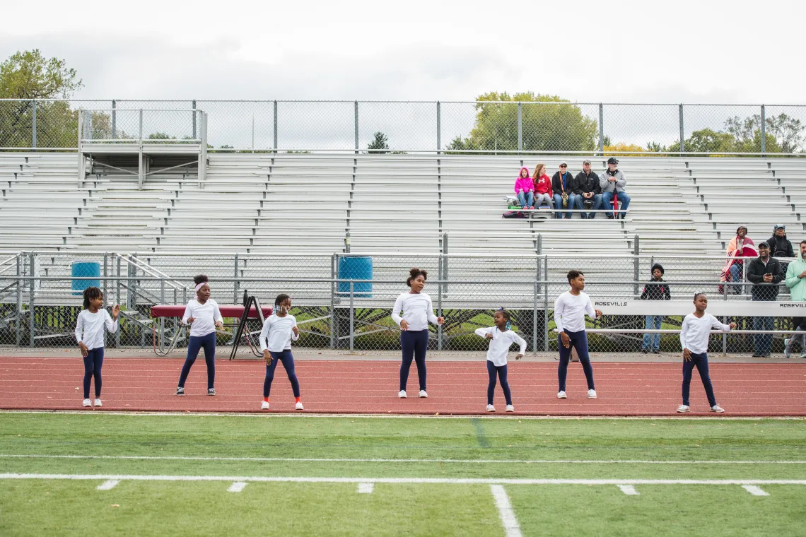 Youth Cheerleading participants practice a routine on the outdoor track at the YMCA