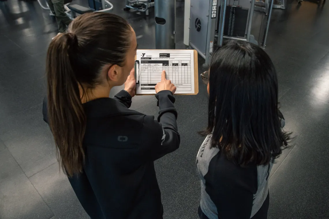 Staff goes over a workout plan with a member at the YMCA