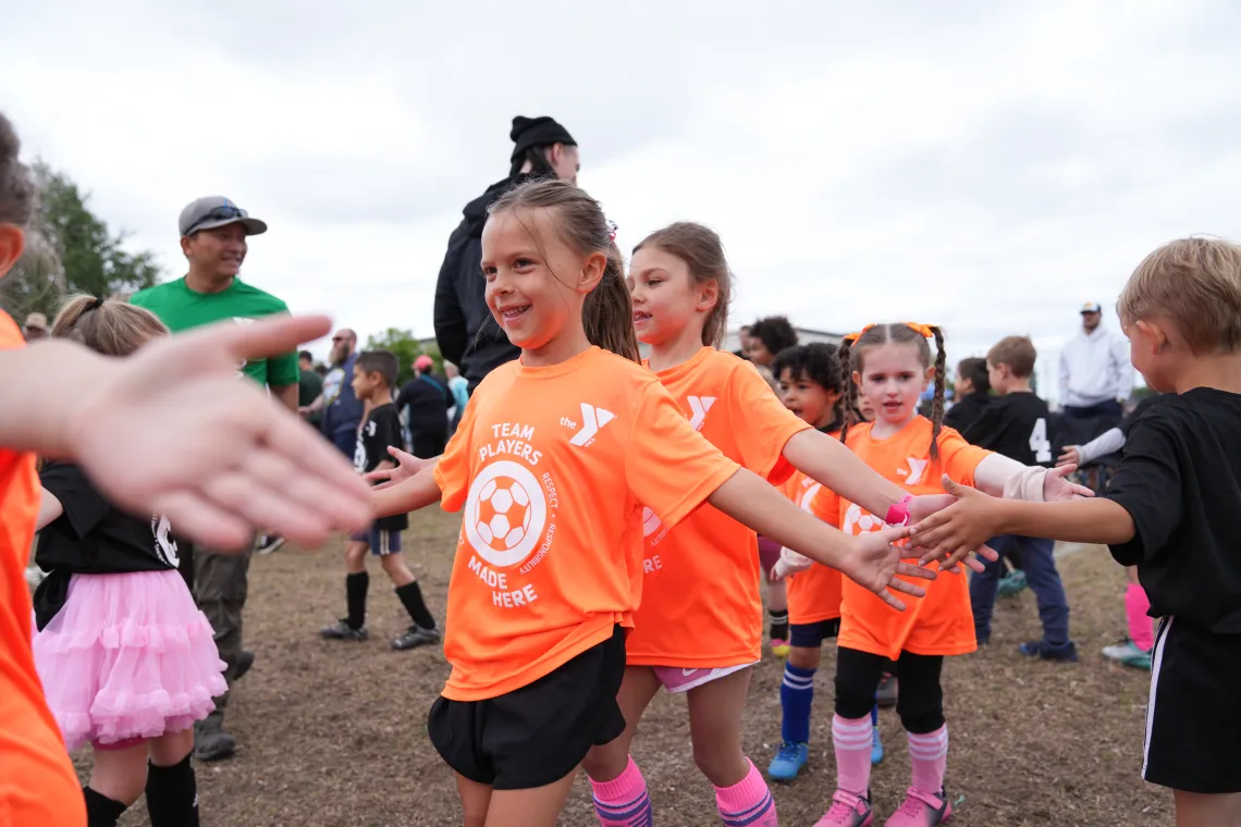 Action shot of a high five line at the end of a good soccer game at the YMCA