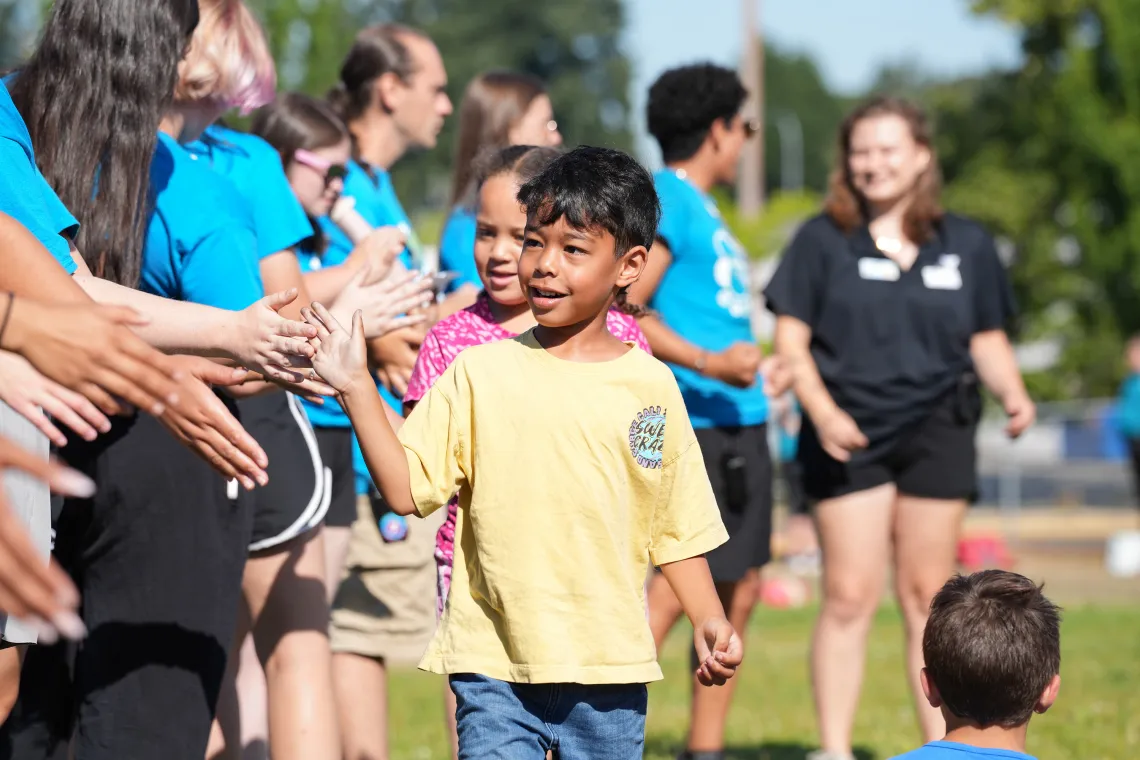 Smiling Child High Fiving Group at YMCA Summer Day Camp