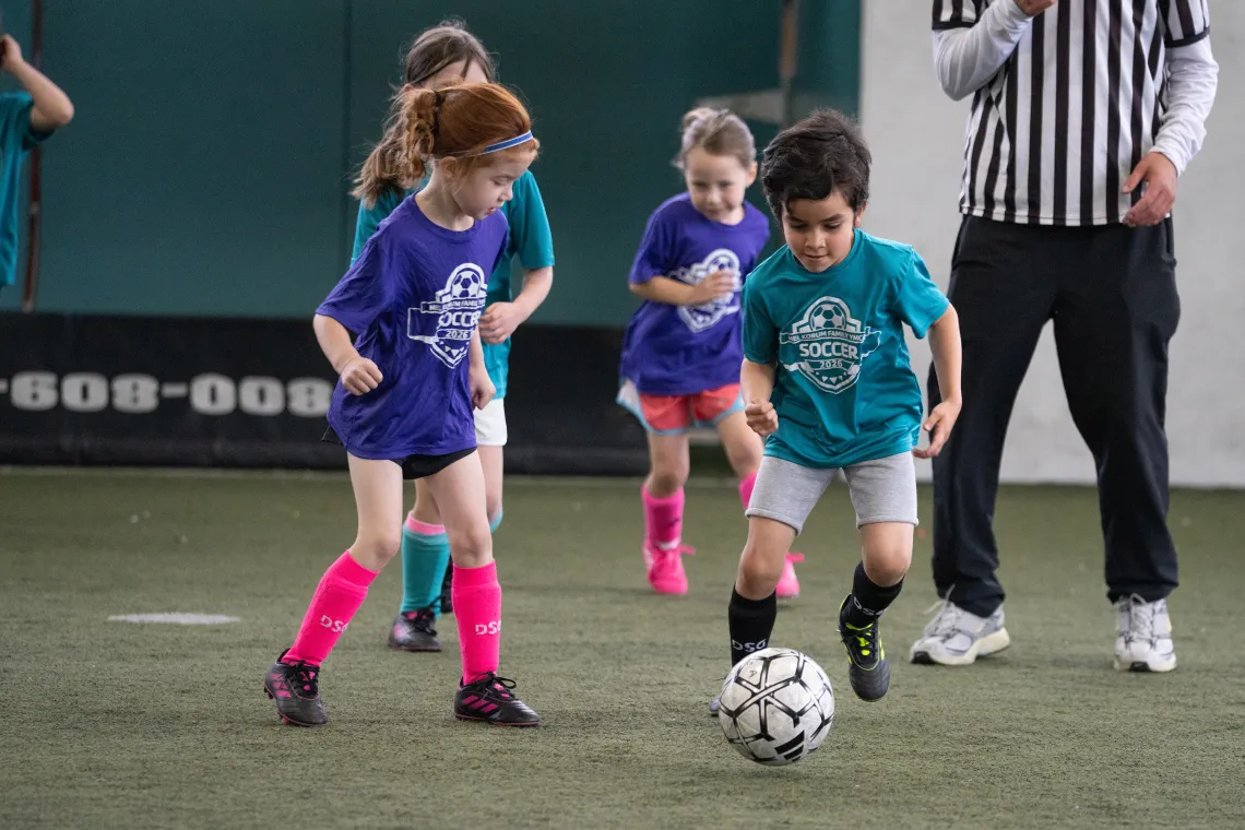 Girl and Boy Dribbling Down YMCA Indoor Soccer Field 