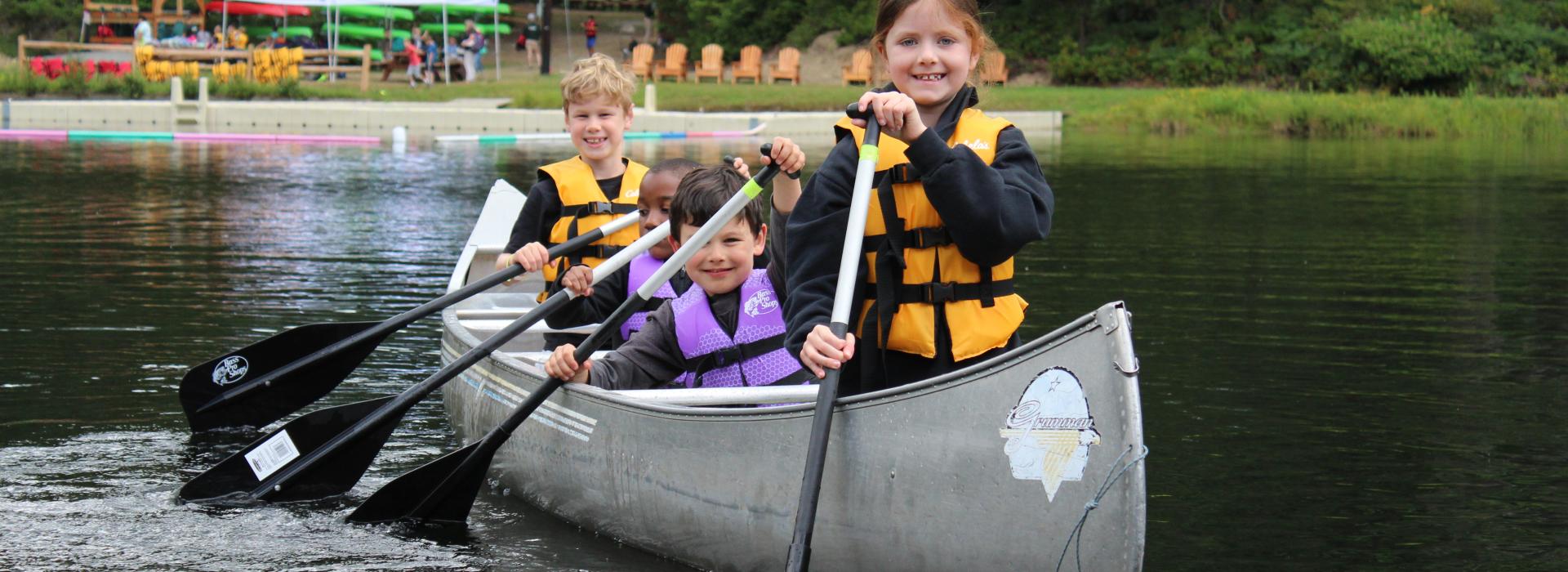 Four children canoeing at Camp Lake Helena