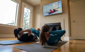Mother and daughter doing sit ups together at home