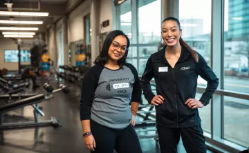 Wellness Coach Franchesca and a young woman member smile proudly at the camera.
