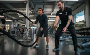 KickStart coach Bryce, provides technique support on the ropes at the University YMCA Student Center to a member.