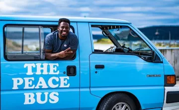 Kwabi throws up a peace sign from the window of his Peace Bus
