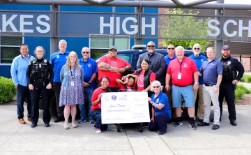 Lakewood community members smiling with a large check raised by the community and the Lakewood Police department at the YMCA