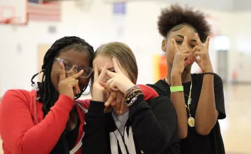 A group of friends flash peace signs while hanging out at Teen Late Nite at the YMCA