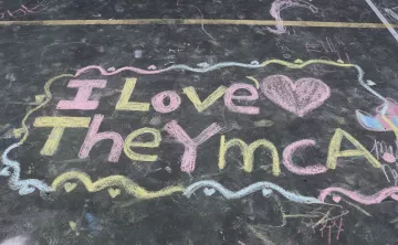 Sidewalk chalk art from a YMCA camper reading "I love the YMCA"