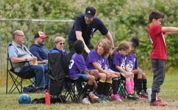 Youth Soccer coach boosts the morale of the benched players during a soccer game at the Gordon Family YMCA