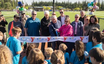 Ribbon‑cutting ceremony at the Gig Harbor YMCA sports field with community members and youth.