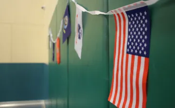 Small U.S., Navy, Coast Guard, and Marine Corps flags hanging on a green indoor wall.