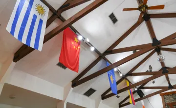 International flags hang from the wooden rafters inside the Lodge at Camp Seymour, showcasing the camp's welcoming community and global connections.