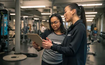 YMCA wellness coach reviews a personalized fitness plan with a member in a modern YMCA fitness center.