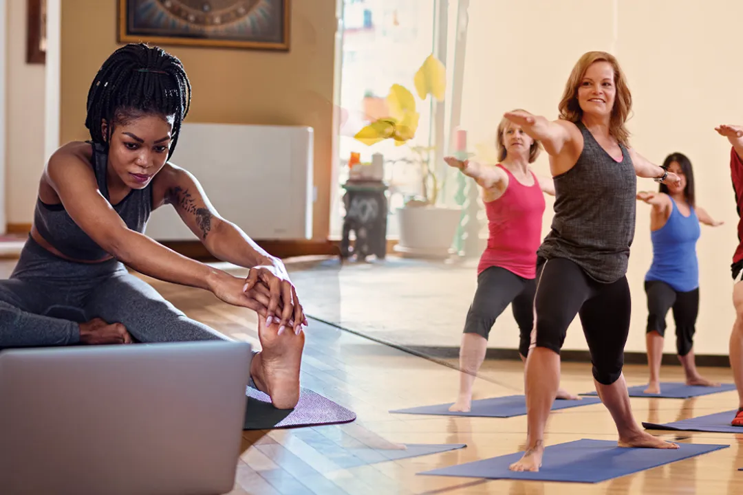 Image of person doing yoga at home stitched with image of gym yoga session
