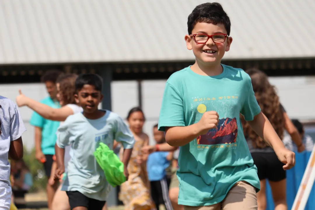 Campers run in the outdoor field at the YMCA during game time.